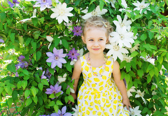 Portrait of a beautiful little girl in summer dress, clematis fl