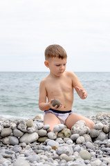 Young Boy Building Stone Wall on Rocky Beach