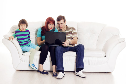 Father, mother and son sitting on the sofa with notebook