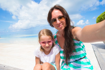 Mother and little girl taking selfie background the sea