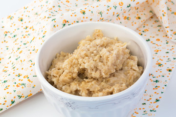 breakfast oatmeal in a white ceramic bowl shabby chic vintage retro selective soft focus
