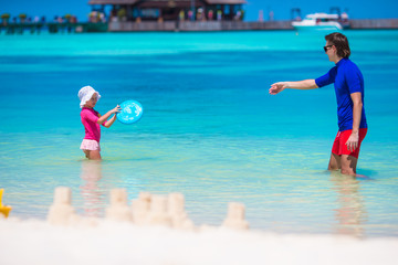 Fototapeta na wymiar Adorable little girl and happy dad playing with beach toys on