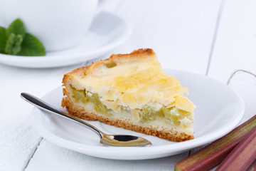 Tasty slice of rhubarb pie on white wooden table.