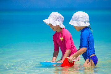 Fototapeta na wymiar Adorable happy little girls have fun at shallow water on beach