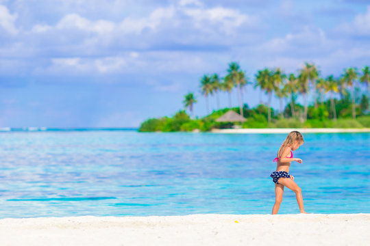 Adorable happy little girl have fun at shallow water on beach