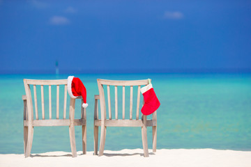 Red Christmas stocking and Santa Hat on chair at tropical white