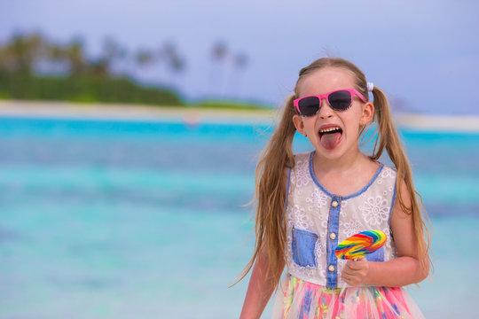 Adorable little girl with lollipop on tropical beach vacation