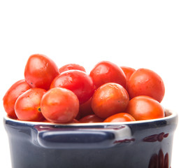 Bite sized red cherry grape tomato in blue pot over white background
