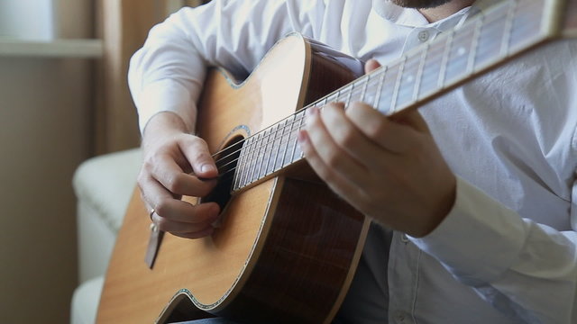guitarist plays on acoustic guitar at home