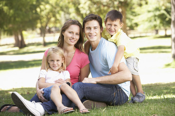 Fototapeta premium Young Family Sitting in Park