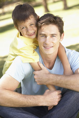 Father And Son Relaxing In Park Together