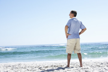 Senior Man On Holiday Standing On Sandy Beach