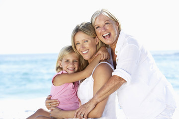 Grandmother With Daughter And Granddaughter Embracing On Beach Holiday