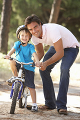 Fototapeta na wymiar Father Teaching Son To Ride Bicycle