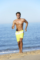 Fototapeta na wymiar Young Man Running Along Summer Beach
