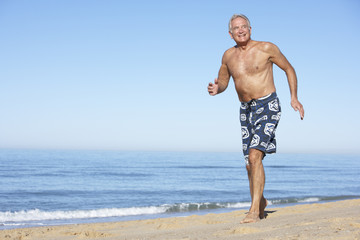 Fototapeta na wymiar Senior Man Running Along Summer Beach