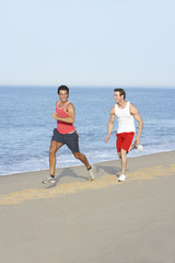 Two Young Men Jogging Along Beach