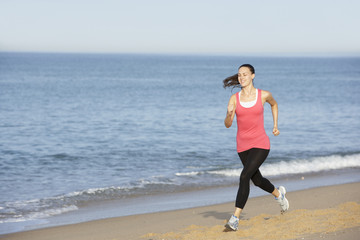 Young Woman Jogging Along Beach