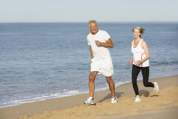 Senior Couple Jogging Along Beach