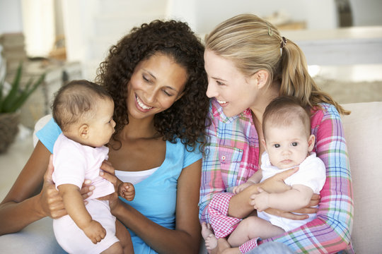 Two Young Mothers On Sofa At Home