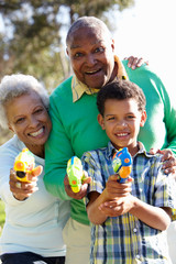Grandparents And Grandson Shooting Water Pistols