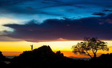 man is taking a photo and standing on rock on beautiful sunset o