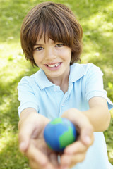 Young Boy Playing Holding Model Of Globe In Park