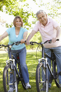 Senior Hispanic Couple Cycling In Park