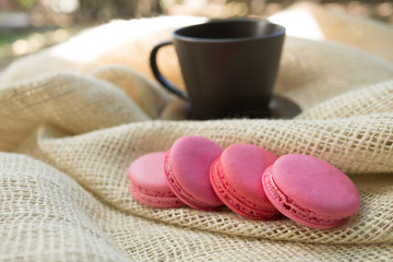 Pink macarons and a coffee mug on hessian fabric - selective foc