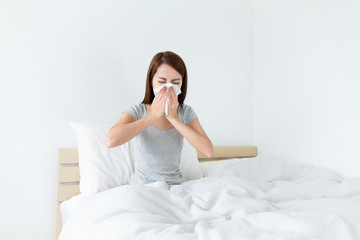 Young lady sneeze on the bed and need more rest
