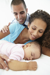 Parents With Sleeping Baby Daughter At Home