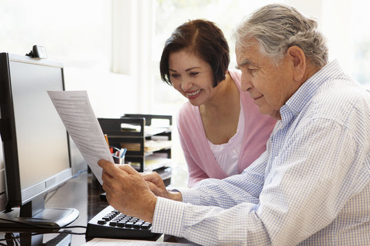 Senior Hispanic couple working on computer at home