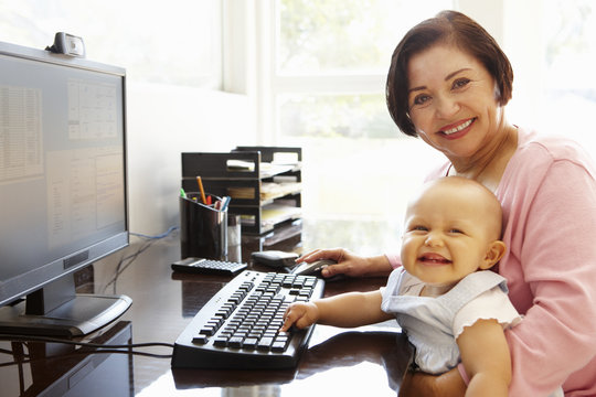 Senior Hispanic Woman With Computer And Baby