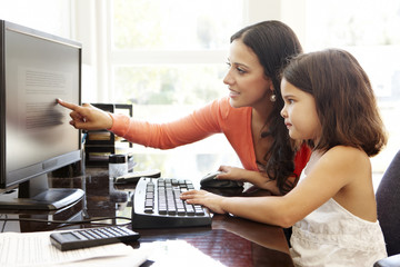 Hispanic mother and daughter using computer at home