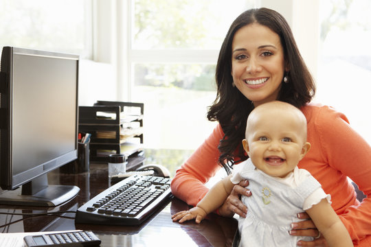 Hispanic mother with baby in working home office