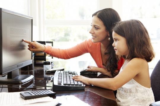 Hispanic mother and daughter using computer at home