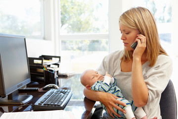Mother working in home office with baby