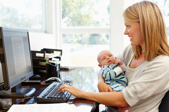 Mother working in home office with baby