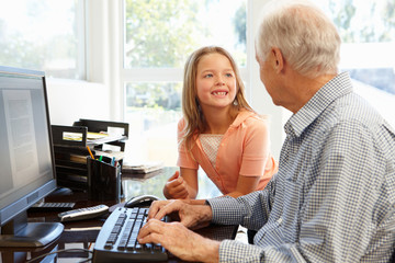 Senior man and granddaughter using computer