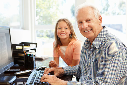 Senior man and granddaughter using computer