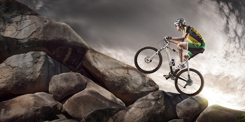 Fototapeta na wymiar Sport background. Cyclist climbing on a rock. 