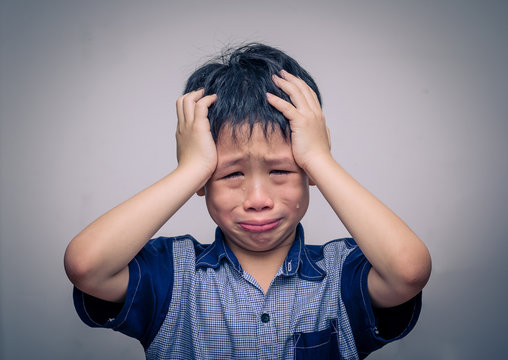 Asian boy crying over dark background