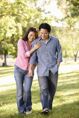 Asian couple walking hand in hand in park