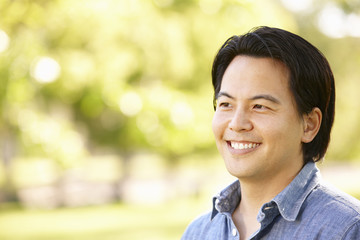 Head and shoulders portrait Asian man outdoors