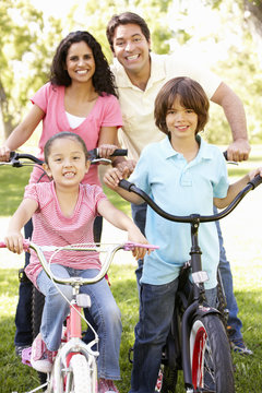 Young Hispanic Family Cycling In Park