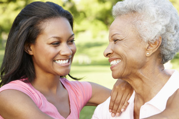 African American Mother And Adult Daughter Relaxing In Park