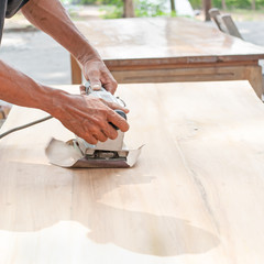 Hand of worker sanding the old wood table.