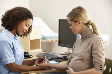 Nurse taking blood sample from pregnant woman