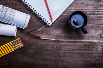Copybook pencil blueprints wooden meter and cup of coffee on pin