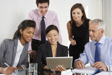 Group Of Business People Having Meeting Around Tablet Computer At Glass Table